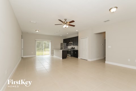 A spacious room with a ceiling fan and a kitchenette.