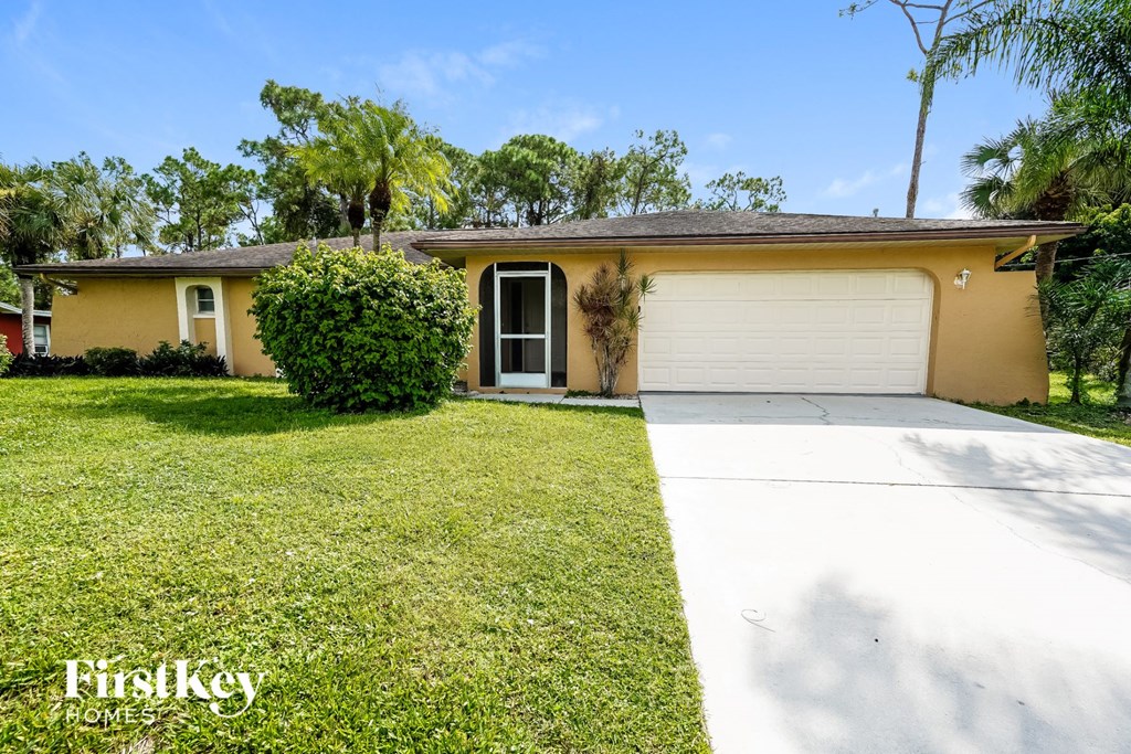 A yellow house with a white garage door and a green lawn.