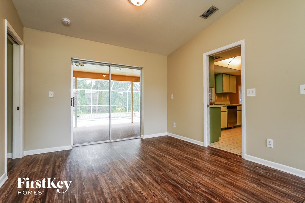 A room with wooden floors and a sliding glass door leading to a patio.