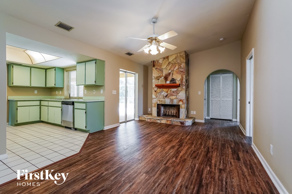 A spacious living room with wood flooring and a fireplace.