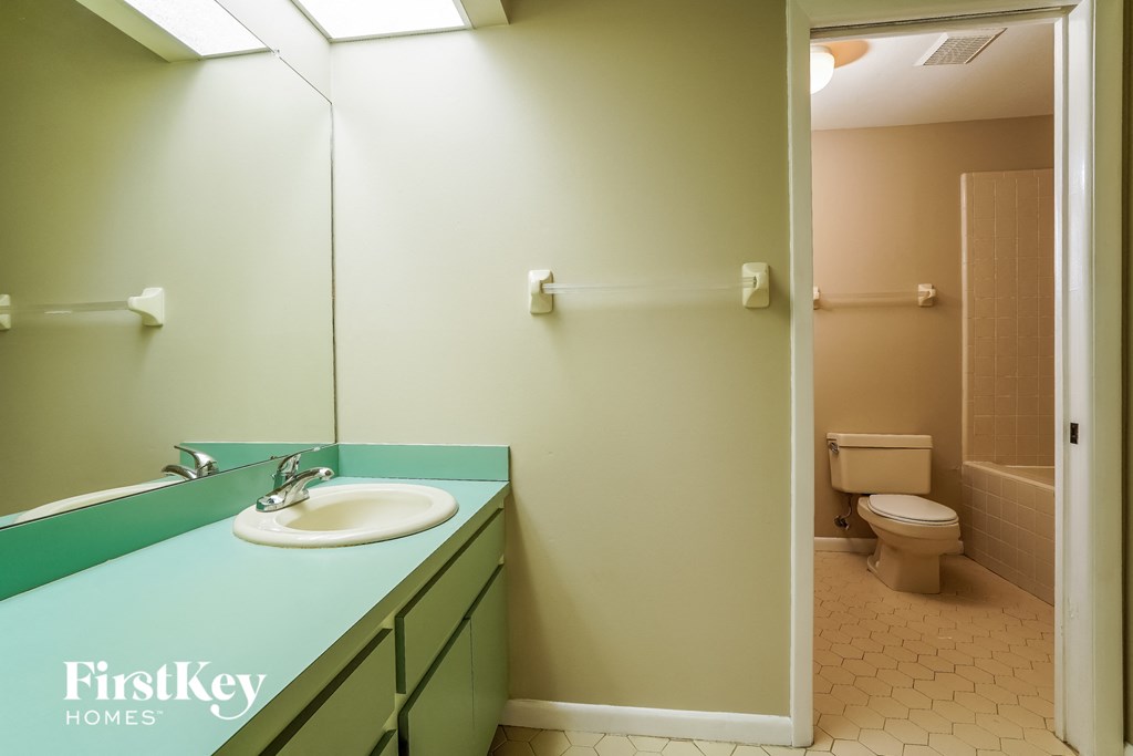 A bathroom with a green counter top and a white sink.