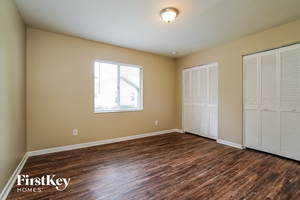 A room with wooden floors and a window with blinds.