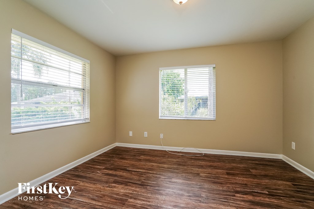 A room with wooden floors and two windows.