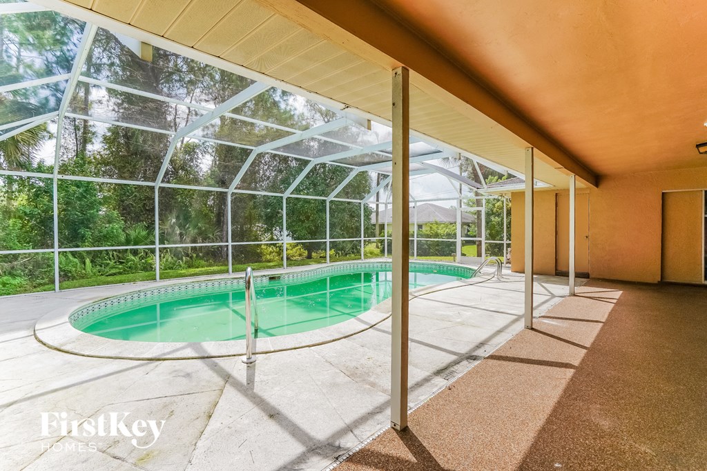 A swimming pool inside a house with a glass wall.