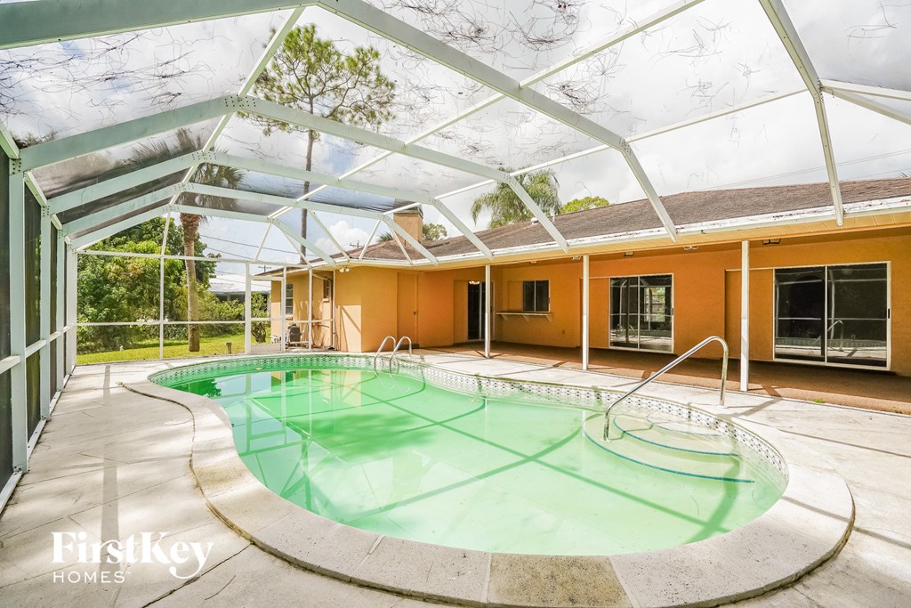 A swimming pool under a glass roof in a house.