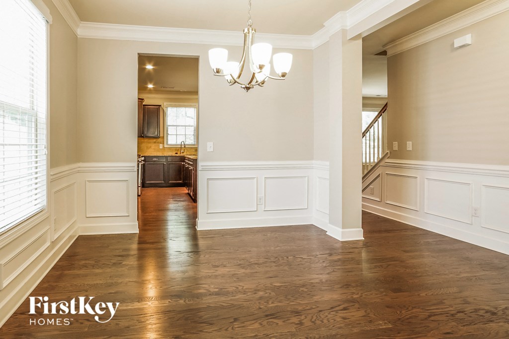 A spacious room with wooden floors and a chandelier.
