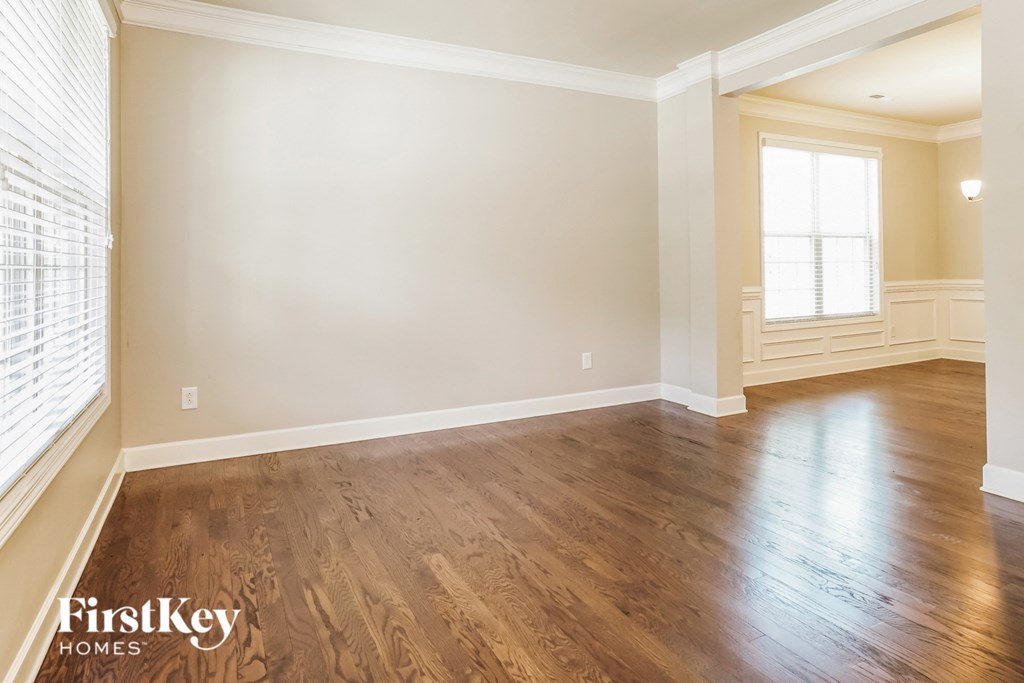 A room with wooden flooring and a window with blinds.