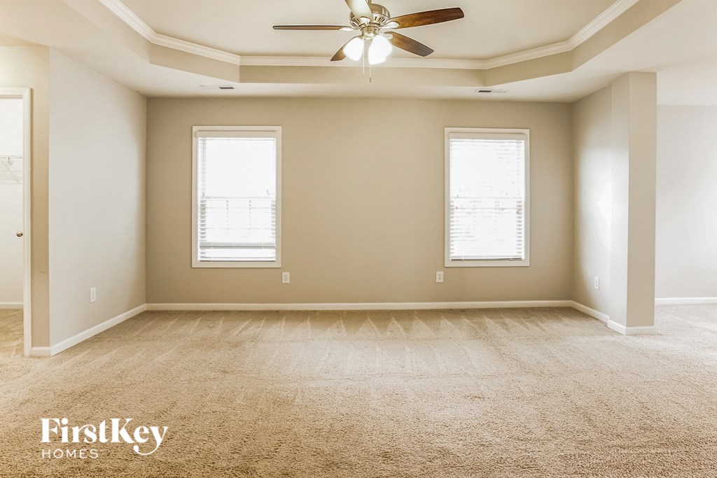 A spacious room with a carpeted floor and a ceiling fan.