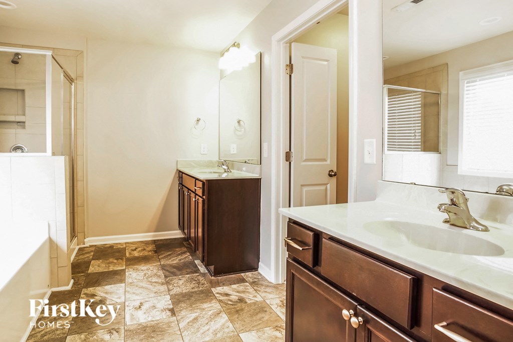A bathroom with a brown vanity and a white sink.