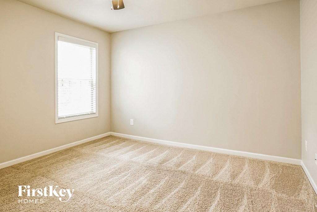 A room with a carpeted floor and a window letting in light.