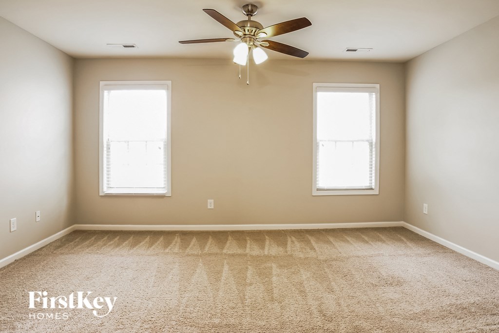 A spacious room with a carpeted floor and a ceiling fan.