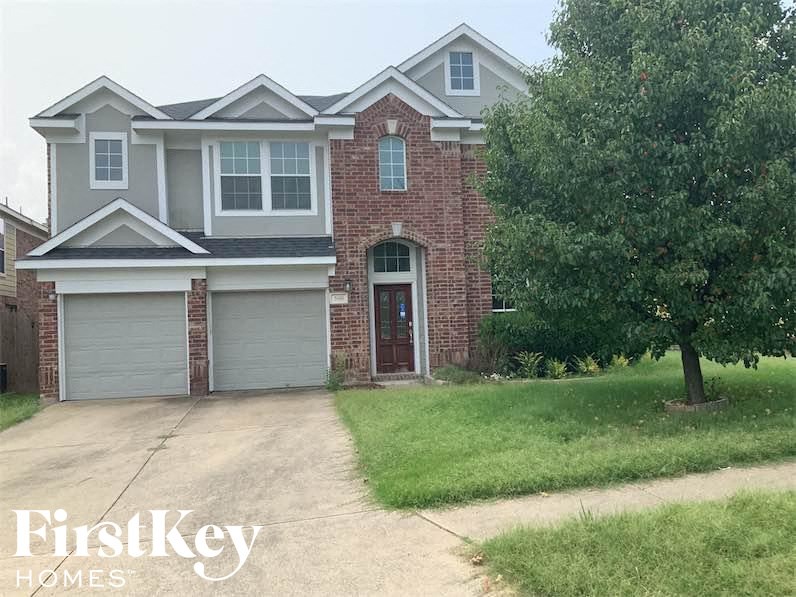 a brick house with a driveway and a tree