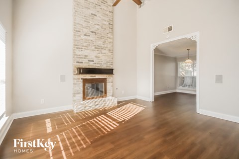 a living room with a brick fireplace and wooden floors