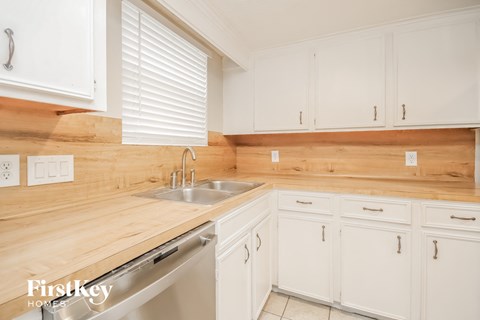 a kitchen with white cabinets and wooden counter tops and a sink