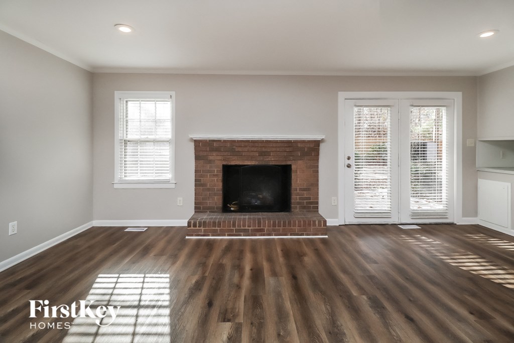 a living room with a brick fireplace and wooden floors