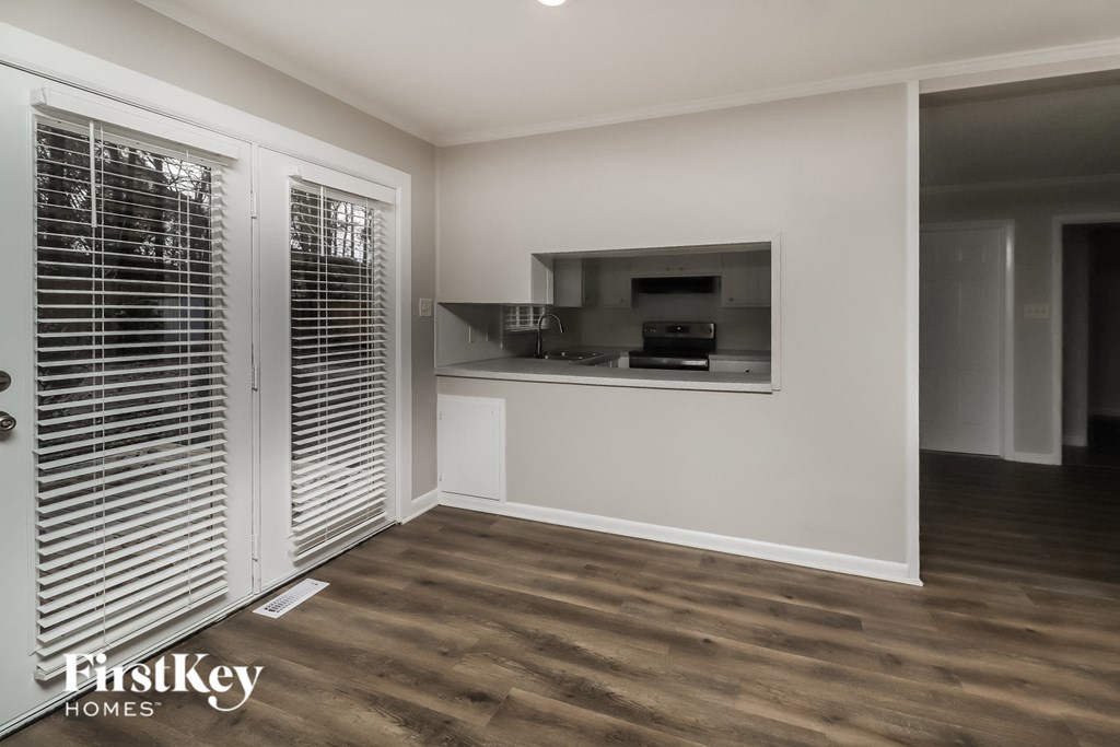 a living room with wooden floors and a kitchen