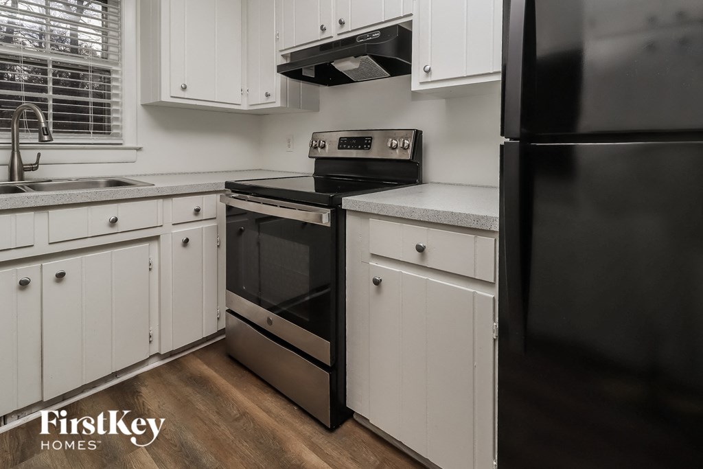 a kitchen with white cabinets and black appliances
