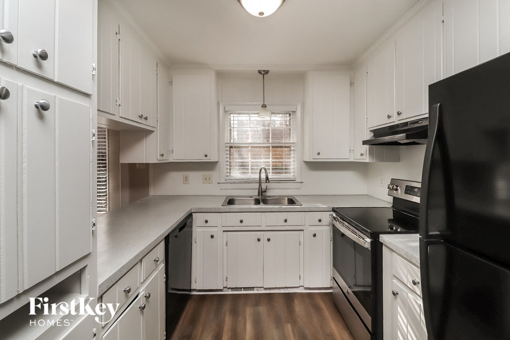 a kitchen with white cabinets and black appliances