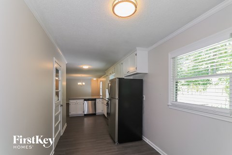 A kitchen with a black refrigerator and white cabinets.