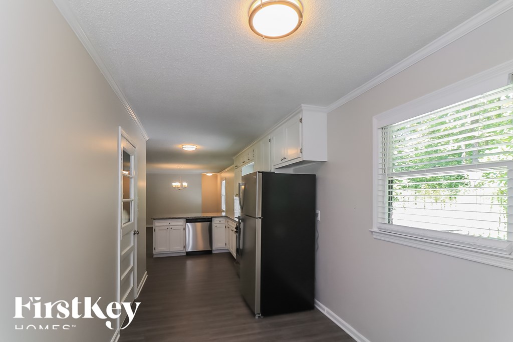 A kitchen with a black refrigerator and white cabinets.