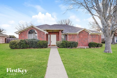 a brick house with a white door and a lawn