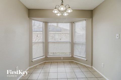 an empty dining room with three windows and a chandelier