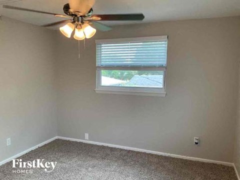 an empty room with a ceiling fan and a window