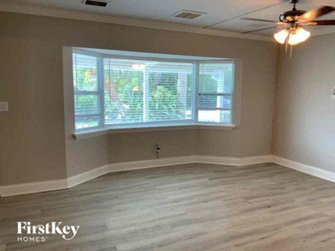 an empty living room with a large window and a ceiling fan
