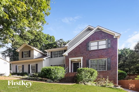 a brick house with white siding and a lawn