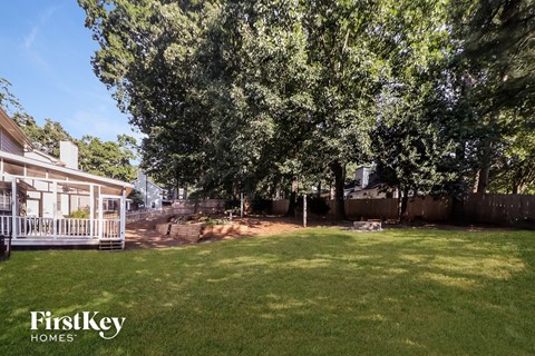 a backyard with trees and a fence and a house