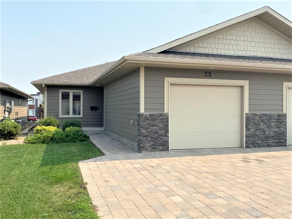 a gray house with a white garage door and a brick sidewalk