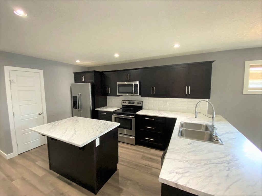 a kitchen with black cabinets and white marble counter tops