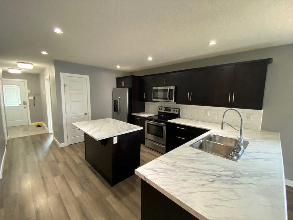 a renovated kitchen with marble counter tops and black cabinets