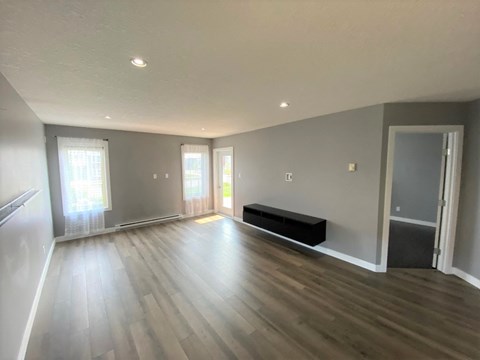 a living room with hardwood floors and grey walls and a black couch