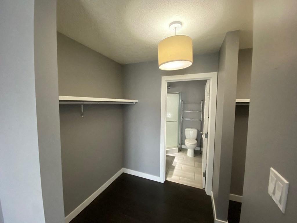 a bathroom with a toilet and a hallway with a light hanging above it