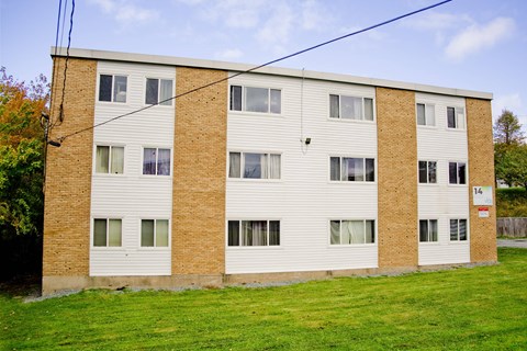A brick building with a white trim and a red sign on the right side.