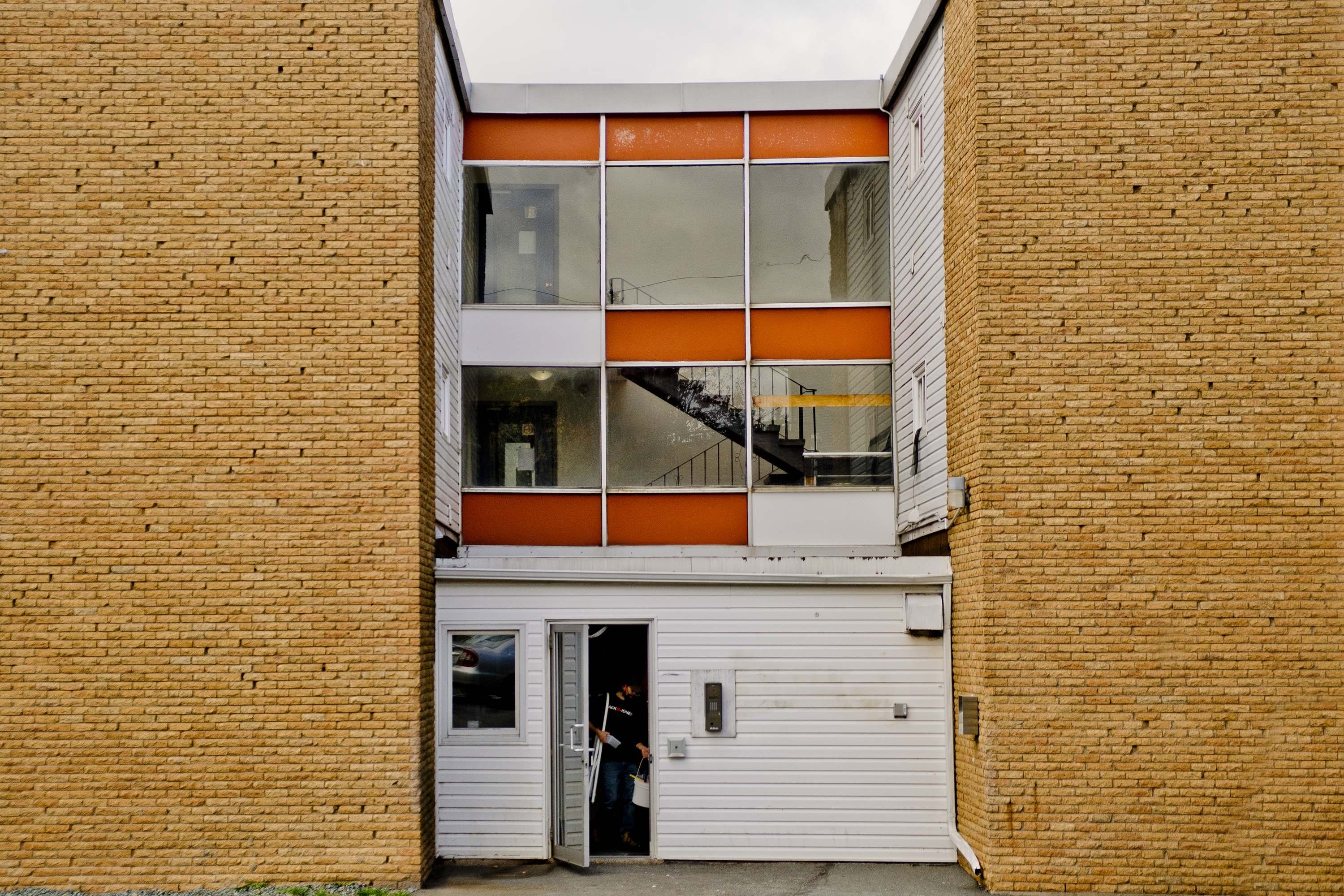 A man is entering a building through a white door.