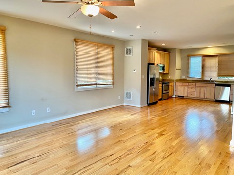 an empty kitchen and living room with wood floors and a ceiling fan