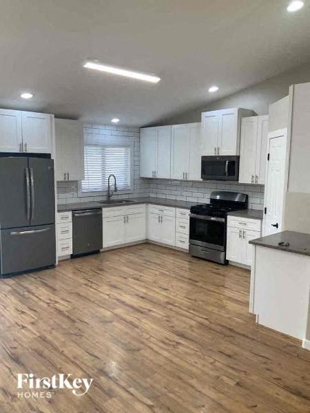 A kitchen with wooden floors and white cabinets.