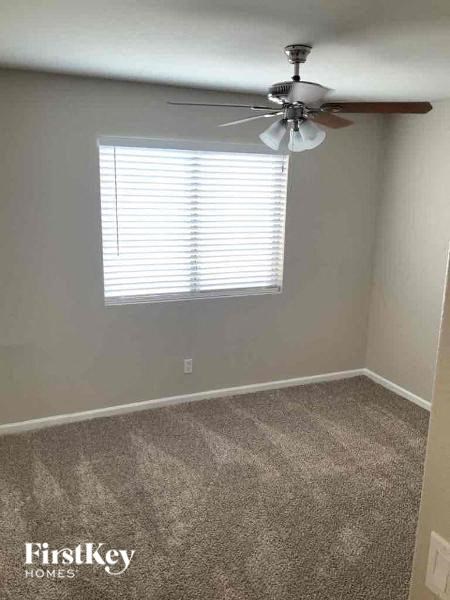 A room with a fan and a window with blinds.
