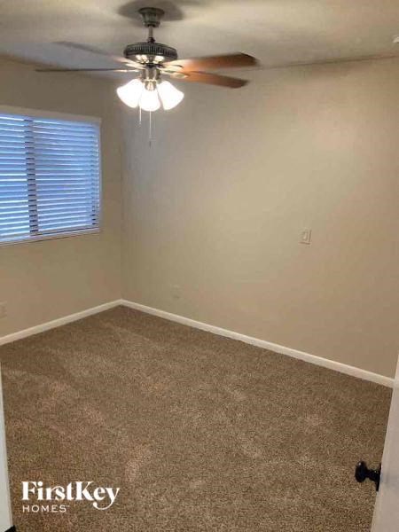 A room with a carpet floor and a ceiling fan.