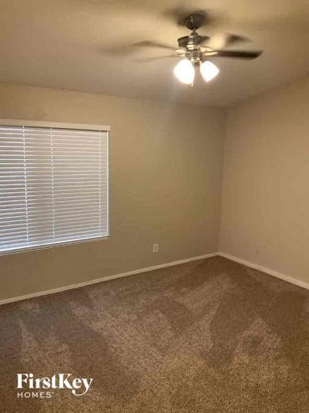 A room with a ceiling fan and a window with blinds.