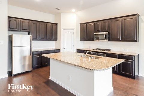 A kitchen with a white island and dark brown cabinets.