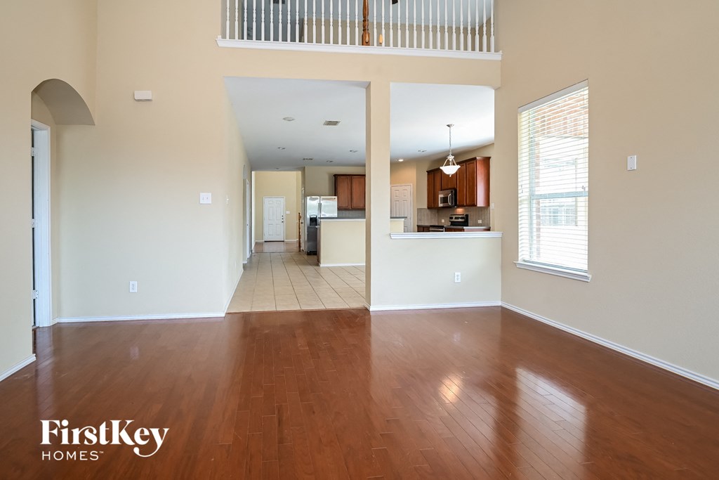 an empty living room with wood floors and a kitchen