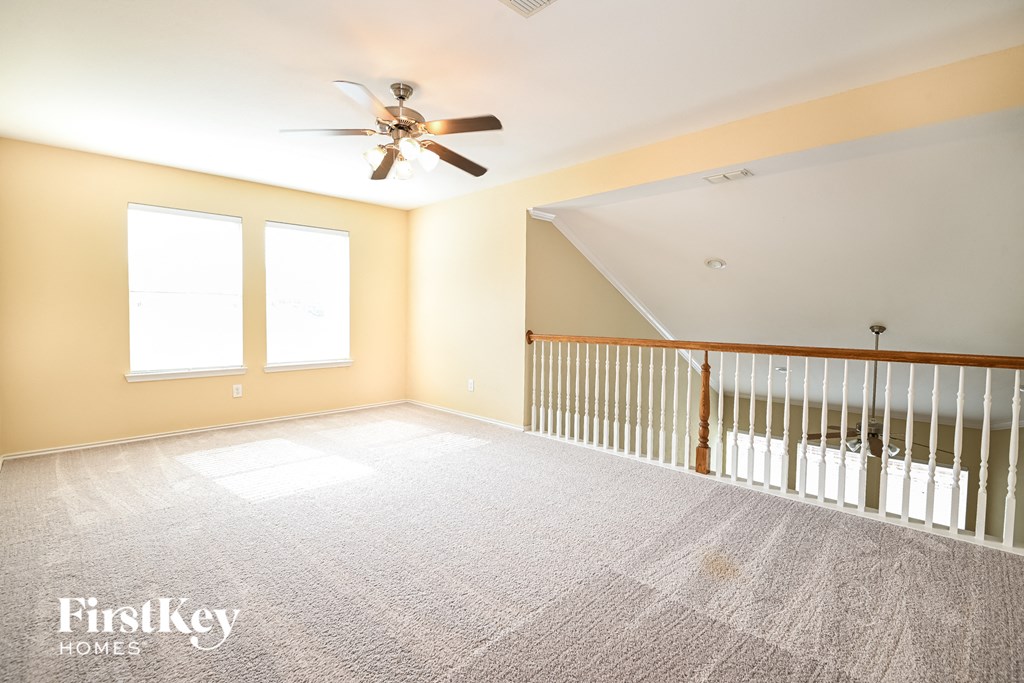 a large empty room with a ceiling fan and a crib