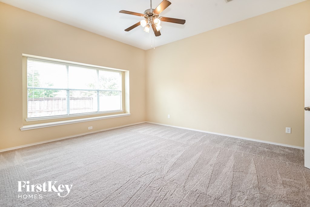 an empty living room with a ceiling fan and a window
