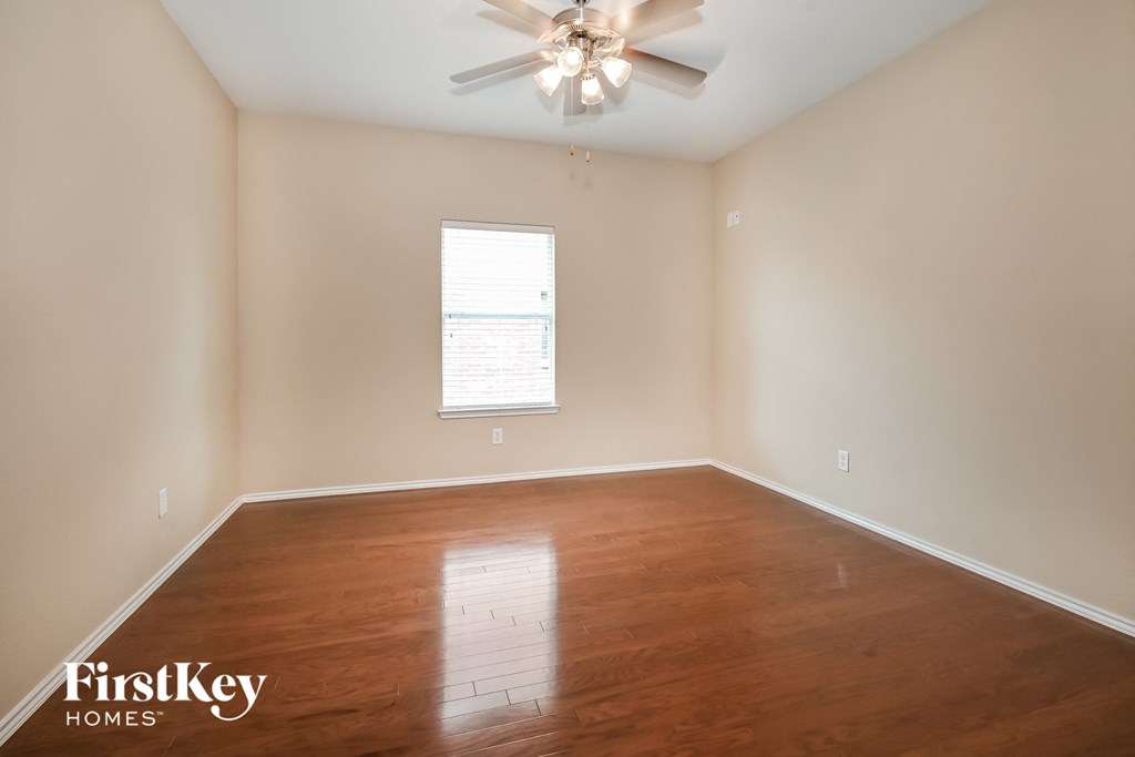 a empty living room with wood floors and a ceiling fan