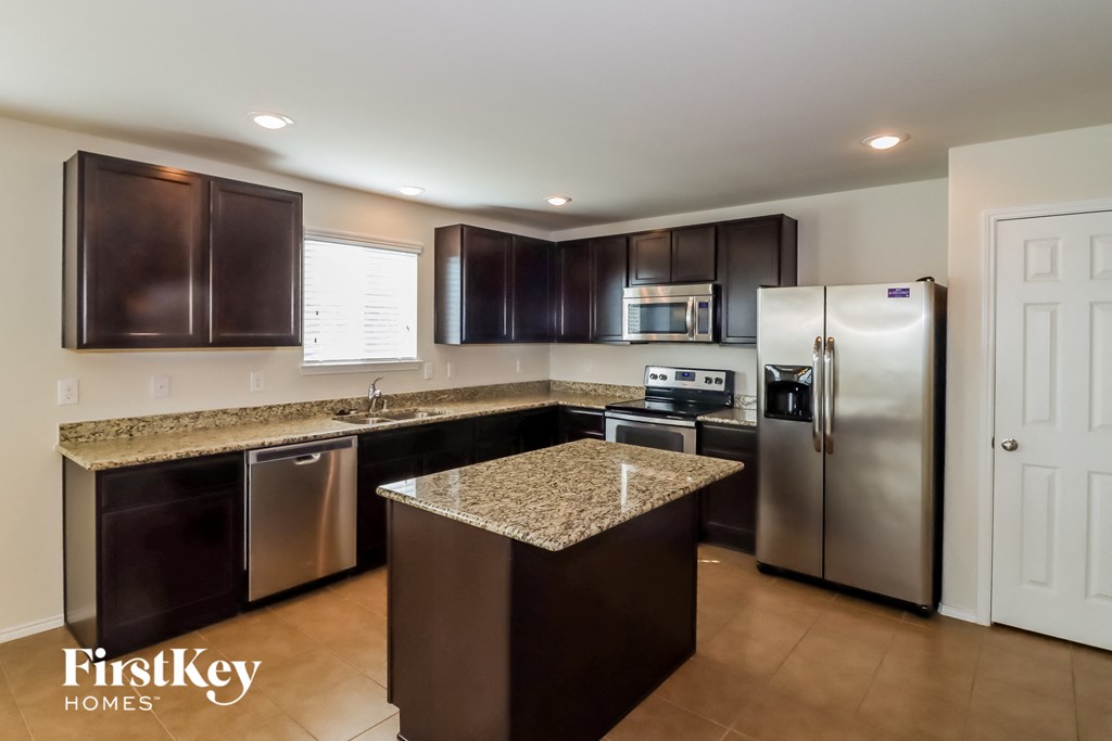 A kitchen with a granite countertop and stainless steel appliances.