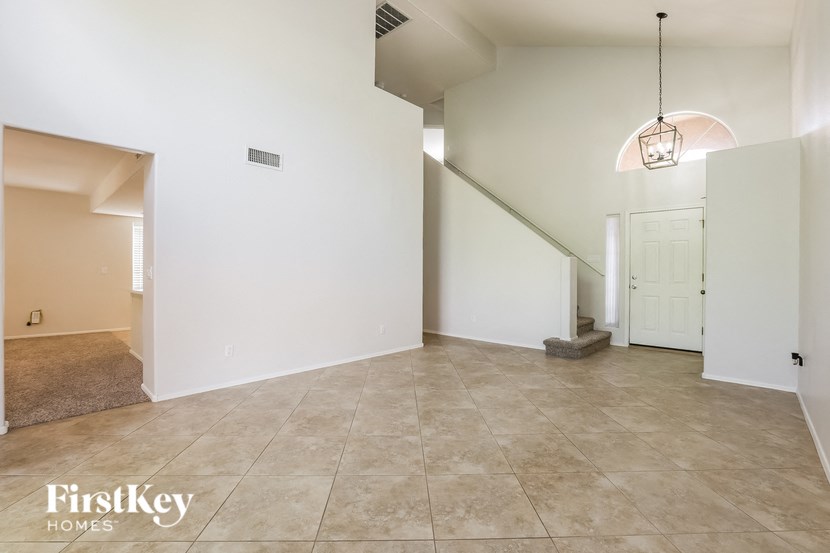 an empty living room with a staircase and a white door