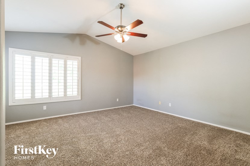 an empty room with a ceiling fan and a window